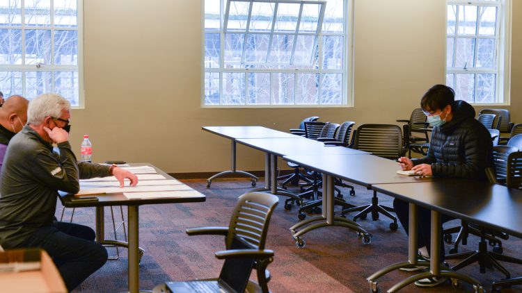 Larry pretends to talk on a phone and looks at the student sitting at the table across from him