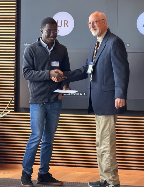 Student shaking hand and  receiving scholarship check on stage